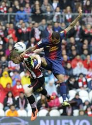 Barcelona's Dani Alves (R) jumps for the ball with Athletic Bilbao's Iker Muniain in Bilbao on April 27, 2013